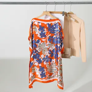 Gedetailleerd overzicht van de oranje bloemige losse dames top met stijlvolle boothals.