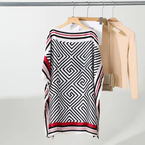 Gedetailleerd shot van een zwart-witte en rode geometrische lichte losse poncho top.