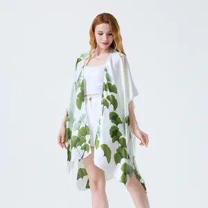 Dettaglio cardigan kimono con stampa foglia di ginkgo verde, tessuto copricostume spiaggia.