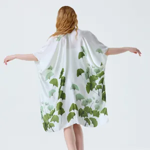 Vista di dettaglio del kimono bianco elegante con stampe botaniche di foglie di ginkgo verdi.