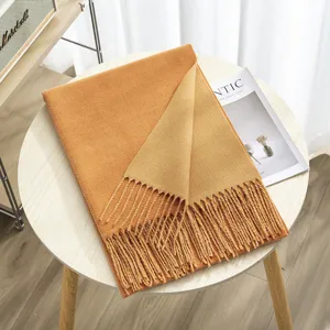 Detailed shot of a cozy double-sided cashmere-feel winter scarf with elegant fringe on a wooden table.