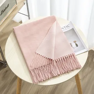 Close-up detail view of soft pink reversible winter scarf with elegant tassel fringe design.