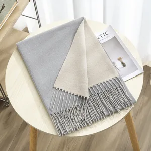 Detailed view of the winter reversible cashmere feel scarf with fringe in grey and beige.