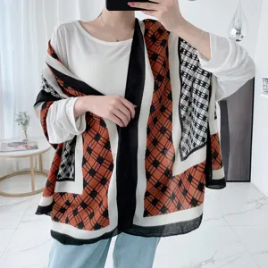 Vue détaillée d'une écharpe écossaise orange et noire pour femme, texture douce et confortable.