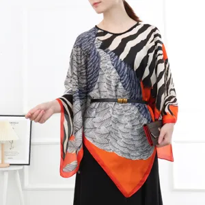 Detail view of the stylish asymmetrical silk scarf blouse with vibrant print and elegant belt.