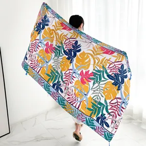 Detail shot of a large tropical leaf print scarf with colorful botanical pattern and tassel trim.