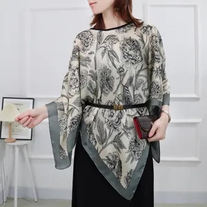 Detail shot of women's floral print sheer asymmetrical cape shawl summer beach cover up top.