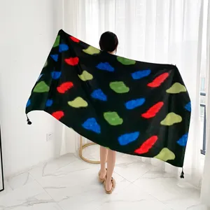 Detailed view of the black shawl featuring colorful abstract prints and tassel edges.