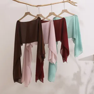 Detailed view of lightweight sheer chiffon shawls and cardigans hanging on a rustic branch.