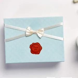 Red wax seal sticker with thank you text on gift box, retro style wedding invitation decor.