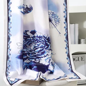 Dettaglio di sciarpa in seta con stampa floreale blu e bianco, elegante scialle da spiaggia.