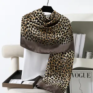 Dettaglio della sciarpa leopardata con tessuto morbido, bordo marrone elegante e bel drappeggio.