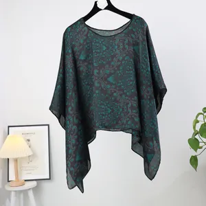 Detailed view of the dark floral silk cape, featuring a loose fit and elegant damask pattern.