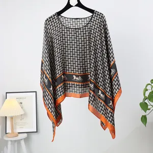 Detailed view of the women's faux silk poncho shawl with classic carriage and chain print.