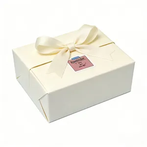 Boîte cadeau ivoire élégante avec nœud en ruban satin et autocollant inspirant pour emballage.