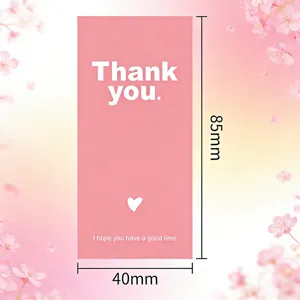 Détail d'autocollant rose merci 85x40mm, fond floral élégant pour cadeaux emballés.