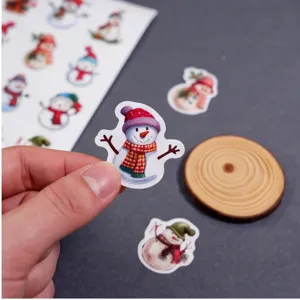 Primer plano de pegatinas navideñas de muñeco de nieve, mano mostrando linda decoración.
