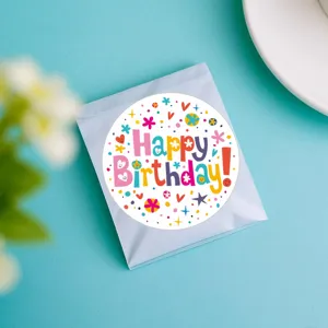 Gros plan détaillé d'un autocollant d'anniversaire rond et coloré sur un fond bleu vif.