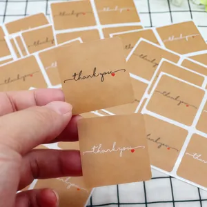 Close-up detail of kraft paper thank you stickers featuring elegant cursive text and red heart.