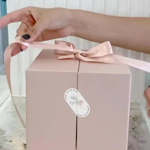 Pink gift box packaging sealing sticker with thank you text and floral design detail.