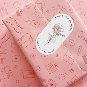 Close-up detail of aesthetic pink floral thank you sticker and gift wrapping paper set.