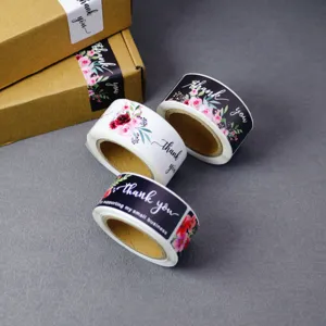 Detail shot of vintage floral thank you sticker rolls on grey background for packaging decor.