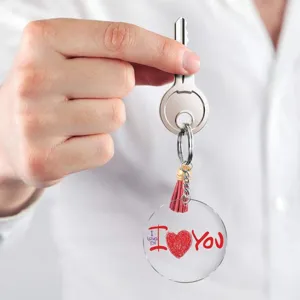 Detail view of transparent acrylic keychain with red leather tassel, romantic heart design.