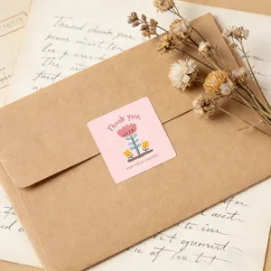 Close-up of a pink square thank you sticker on a kraft envelope with vintage dry flowers.