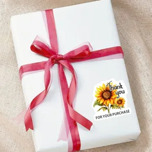 Sunflower thank you sticker detail on gift box with red ribbon, handmade craft sealing label.
