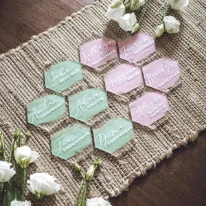 Primer plano de marca sitios de boda de acrílico hexagonal en rosa y verde con nombres.