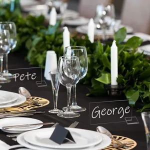 Tarjetas de asiento de acrílico transparente con nombres elegantes escritos a mano en la mesa de boda.