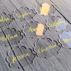 Clear acrylic shell place cards with custom gold names for wedding party table decor.