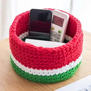 Vue détaillée d'un panier de rangement en corde de coton tricoté style pastèque sur table.