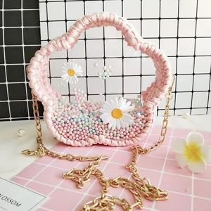 Détail de sac tissé à la main en acrylique transparent en forme de fleur rose.