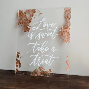 Letrero de boda de acrílico transparente con láminas de cobre y caligrafía blanca para mesa dulce.