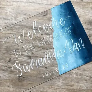 Detalle de cartel de bienvenida de boda de acrílico transparente con texto blanco.