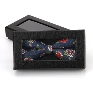 Detailed close-up view of a floral print bow tie inside a black textured gift box.