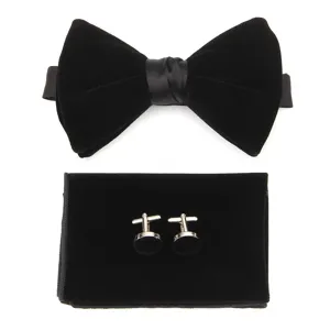 Dettaglio papillon in velluto nero, fazzoletto da taschino e gemelli per abito formale.