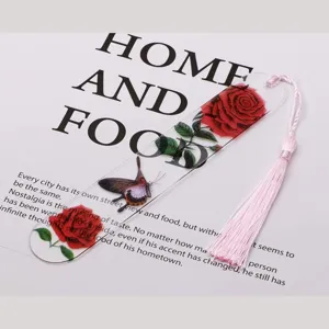 Close-up detail of clear acrylic bookmark with rose and butterfly pattern and pink tassel.