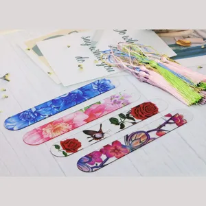 Transparent acrylic bookmarks with colorful floral patterns and tassels detail view.