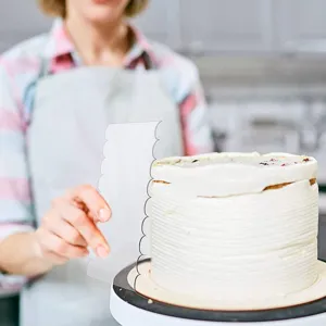 Nahaufnahme Detail des klaren Acryl Kuchenschabers beim Glätten der Creme auf dem Tortenboden.