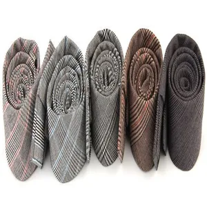 Primer plano de corbatas de cuadros para hombre enrolladas que muestran textura y colores.