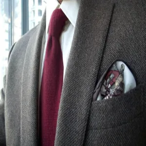 Detalle en primer plano de traje de tweed para hombre, corbata y pañuelo estampado.