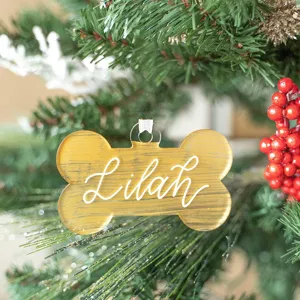 Gold brushed acrylic bone ornament detail hanging on a Christmas tree branch close up shot