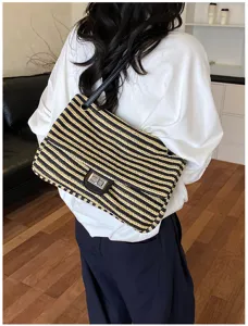Vista detallada de un elegante bolso de hombro de paja a rayas negras y amarillas.