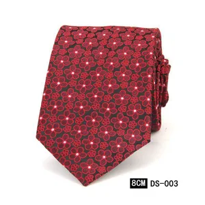 Vista detallada de la corbata tejida con diseño floral rojo y negro, mostrando finas texturas.