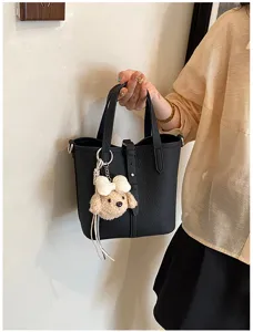 Nahaufnahme der schwarzen Leder Eimer Tasche für Damen mit süßem Plüsch Hund Anhänger.