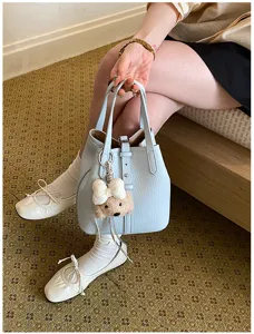 Schicke Leder Eimer Tasche mit einem süßen Plüsch Bären Anhänger für modischen Alltag.