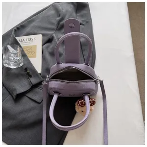 Purple textured bowling handbag stylish crossbody pillow bag with top handles and cute charm.