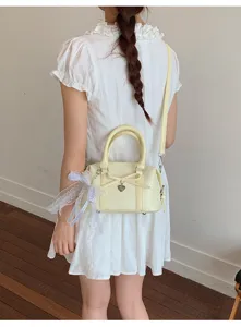 Chic pale yellow women handbag detail, stylish bow and lace decor, elegant crossbody bag.
